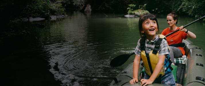 A young girl and woman kayak on a river